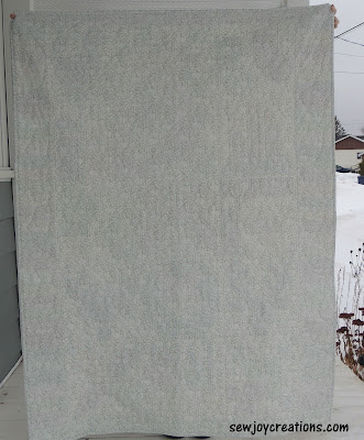 back of Jolly Holly quilt light backing machine quilted