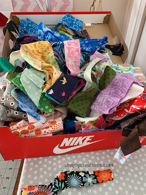 Shoe box full of saved strips fabric strips overflowing from a shoe box