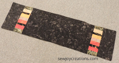 reverse side of churn dash runner black batik runner with scrap strips