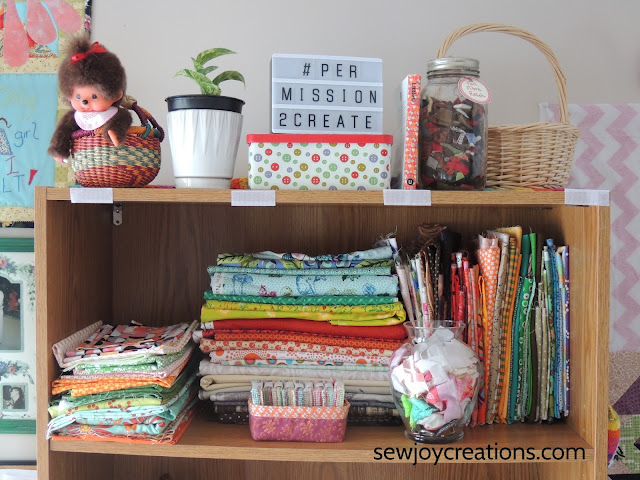 top shelf full of pretty fabrics and my plant on the top fabric folded bookcase display quilt room sewing room